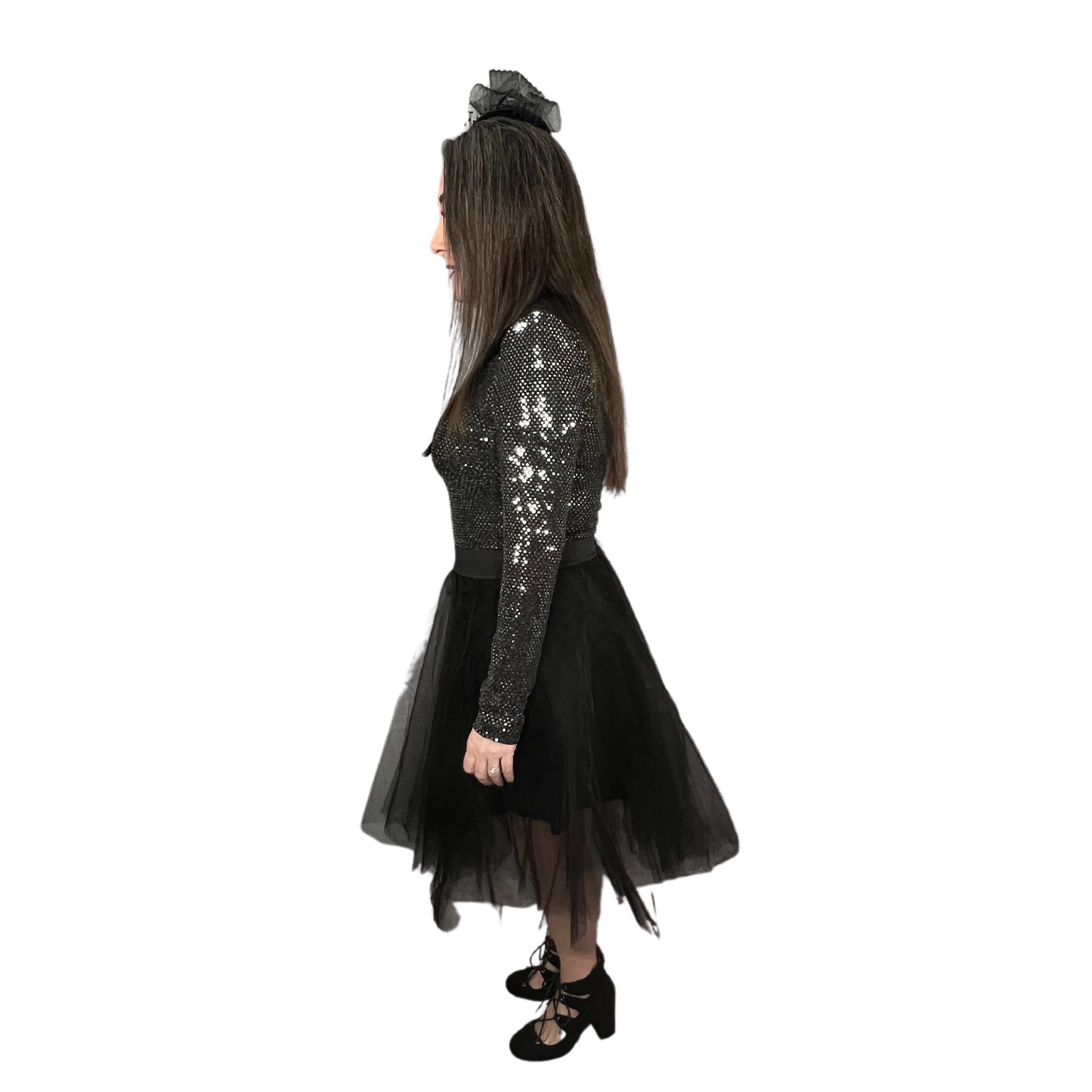 Sideview of woman wearing black tulle skirt with elastic waistband, longsleeve shiny body suit, black lace up heels, lapel collar and stylish vintage hat